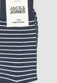 Calzini blu navy in misto cotone con righe bianche orizzontali. Inclusa un'etichetta con il nome del marchio "JACK & JONES" e una descrizione del tipo di prodotto.