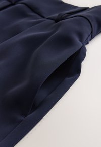 Navy blue dress fabric with a smooth texture and slight sheen, featuring pleating details and a side pocket opening.