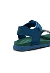 Sandalia infantil en azul y verde con una correa ajustable, plantilla texturizada y suela flexible. Logotipo grabado en la parte trasera.