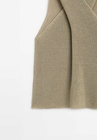 Beige knitted sweater vest with a textured finish, featuring deep armholes and a relaxed silhouette. Soft, breathable fabric.