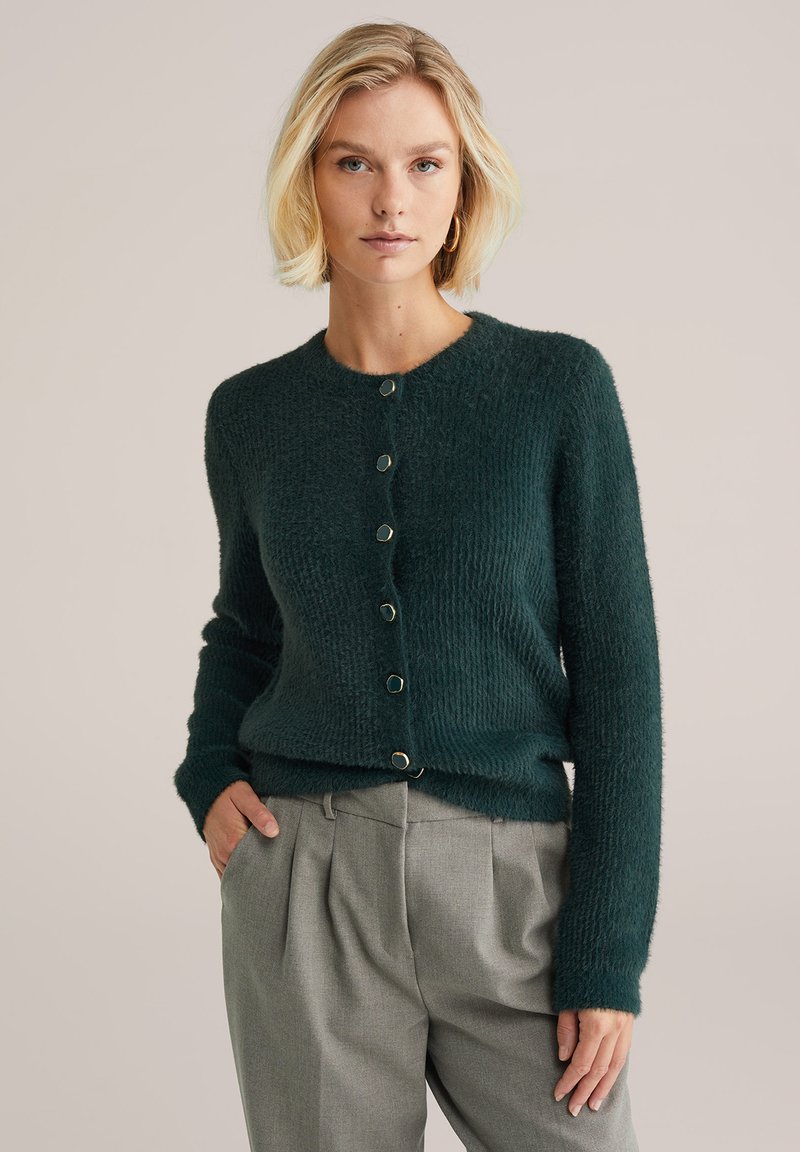 Bosgroene, gevlochten cardigan met een ronde halslijn en vijf ronde knopen. Lange mouwen, licht getailleerde silhouet en zachte stof.