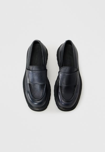 Tumši zilie ādas loafers ar teksturētu apdari, ar platu jostu pāri kājai un biezu melnu gumijas zoli.