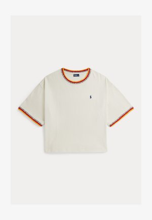 Lühikeste varrukatega valge T-särk, millel on krae ja varrukate ümber kontrastsed punase, kollase ja musta värvi õmblusega ääred ning väike sinine logoga rinnal.