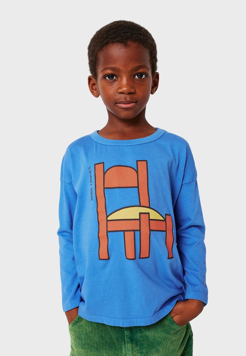 Långärmad blå t-shirt med en grafisk design av en stol och sol i orange och gult. Lättviktig tyg; avslappnad passform.