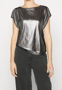 Metallisk svart kortärmad topp med strukturerad yta, vid halsringning och avslappnad passform. Matchas med mörka, lösa byxor.
