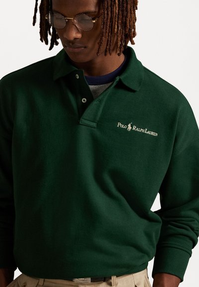 Mørkegrønn polo skjorte laget av et mykt stoff, med brettet krage og brodert logo. Lange ermer med ribbede mansjetter.