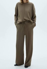 Sweatshirt surdimensionné vert olive et pantalon large assorti en tissu doux, avec une taille à cordon de serrage et des poches latérales.