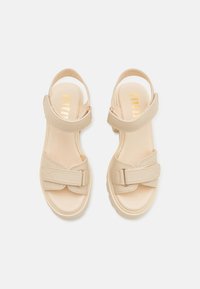 Beige Sandalen mit einem glatten synthetischen Obermaterial, verstellbarem Knöchelriemen und einem strukturierten Kreuzriemendesign mit einem leichten Absatz.