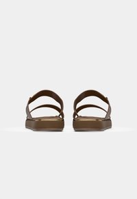 Brązowe sandały z teksturowaną górą, wyposażone w dwa regulowane paski oraz grubą, amortyzowaną podeszwę. Subtelny złoty akcent na krawędzi podeszwy.