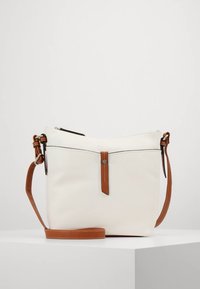 Witte leren crossbodytas met een bruine leren band, voorzien van een ritssluiting en een decoratieve leren lus aan de voorkant.