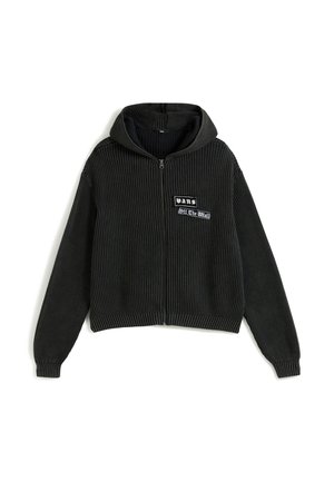Svart ribbad zip-up hoodie med framstående "Vans Off The Wall" logopatch och långa ärmar på en vit bakgrund.