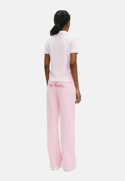 Lichtroze poloshirt met korte mouwen, gecombineerd met lichtroze wijde broek met geborduurde tekst op de achterkant. Gladde katoenstructuur.