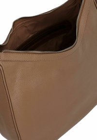 Sac à main en cuir tan avec une texture lisse et une fermeture éclair. L'intérieur comprend deux compartiments et une poche zippée pour l'organisation.