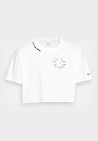 Vit croppad t-shirt med korta ärmar. Framsidan har en flerfärgad cirkulär grafik med orden "SANNING LEV DIN." Texten "KÄRLEK TRANSFORMERAR" finns på kragen.