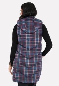 Odpínací vesta v námořnickém károvaném vzoru s fialovými, tyrkysovými a bílými akcenty, se sukní a žebrovaným prošíváním. Nastavitelná bočními knoflíky.