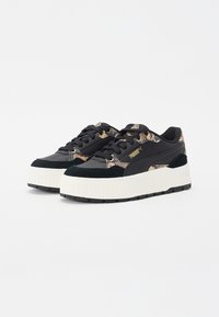 Schwarze Sneakers mit einer strukturierten Oberseite, die ein Schlangenhautmuster in Gold und Beige zeigt, einer dicken weißen Plattformsohle und einer schwarzen Gummilaufsohle.