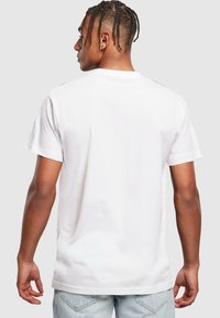 White cotton t-shirt with short sleeves, a crew neckline, and a relaxed fit. The back features a smooth texture and minimal stitching details.