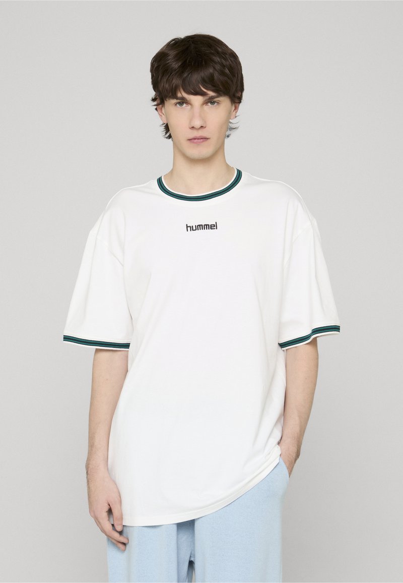 T-shirt en coton blanc avec col ras du cou, accents côtelés verts sur les manches et le col. Présente un logo "hummel" noir sur la poitrine.