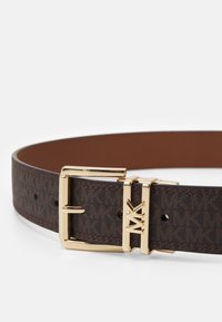 Cintura in pelle marrone a motivi con fibbia in metallo dorato e logo inciso. Il design presenta una finitura liscia e numerosi fori di regolazione.