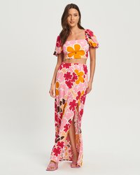 Completo a due pezzi con motivo floreale, composto da un crop top con maniche a sbuffo nei colori rosa, rosso e arancione, abbinato a una maxi gonna lunga con spacco.