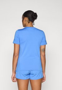 Maglietta sportiva azzurro chiaro con maniche corte e scollo rotondo, abbinata a pantaloni corti coordinati. Tessuto morbido e design minimalista.