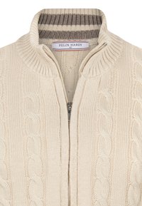 Cremefarbener Strickzipper mit Kabelmuster, geripptem Kragen und braun gestreiftem Innenfutter. Etikett: "FELIX HARDY", Größe M.