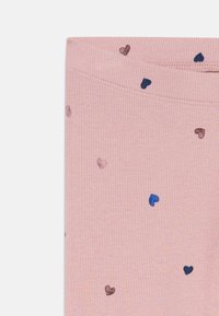 Rosa gerippter Stoff mit verstreuten kleinen blauen und lila Herzmustern, zeigt eine sauber genähte Bundkante.