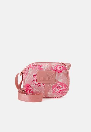 Kleine rechthoekige roze crossbodytas met bloemmotief en Puma-logo, verstelbare riem en ritssluiting.