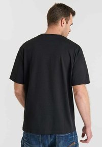 T-shirt nera a maniche corte con collo rotondo, realizzata in tessuto morbido; presenta una vestibilità comoda e un retro semplice senza loghi o fantasie visibili.