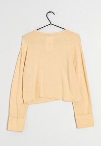 Helle beige, kurze Sweatshirt mit langen, lockeren Ärmeln und gerippten Bündchen. Weicher Stoff mit glatter Textur und leicht gerundetem Ausschnitt.