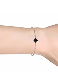 Bracciale in argento con un prominente gemstone quadrato nero al centro, presentato su un polso umano.