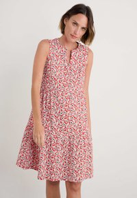 Rochie roșie fără mâneci cu un model floral, având flori albe și albastre, decolteu în V și fustă evazată. Țesătură netedă și ușoară.