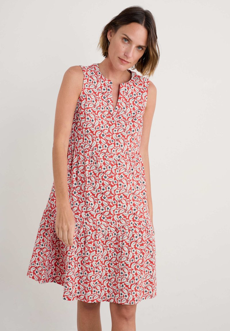 Rochie roșie fără mâneci cu un model floral, având flori albe și albastre, decolteu în V și fustă evazată. Țesătură netedă și ușoară.