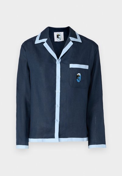 Mornarsko srajco iz lana z svetlo modrim ovratnikom in obrobo žepa. Ima žep na prsih z vezenim motivom. Zapenjanje s gumbi spredaj.