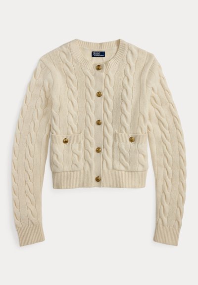 Crèmekleurige kabelgebreide cardigan met ronde hals, lange mouwen, twee voorzakken en zes gouden knopen middenvoor.