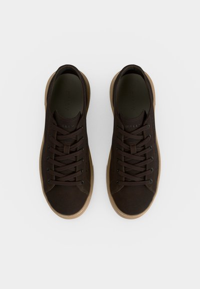 Ζευγάρι σκούρα καφέ αθλητικά με κορδόνια και μπεζ λαστιχένιες σόλες, από ψηλά πάνω σε λευκό φόντο.