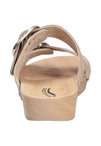 Light beige sandal with multiple suede straps and metallic accents. Features a wooden platform sole with engraved logo.