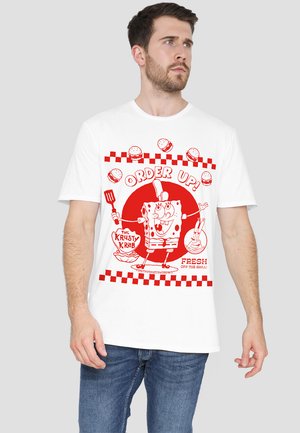 White t-shirt featuring a red graphic design of a cartoon character holding a spatula, with checkerboard border and text "ORDER UP!"