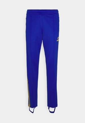Blaue Adidas-Trainingshose mit gelben Seitenstreifen, elastischem Bund und Fußriemchen an den Säumen.