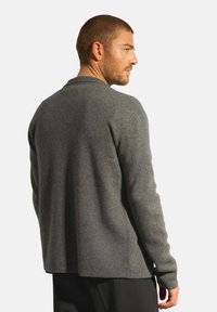 Grå ulltröja med långa ärmar, rund hals och en avslappnad passform. Tyget verkar mjukt och strukturerat, med ett subtilt melerat mönster.