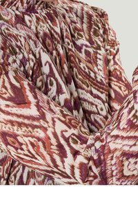 Blouse à manches longues avec un col froncé, présentant un motif abstrait coloré dans des tons de rose, marron et crème. Tissu texturé.