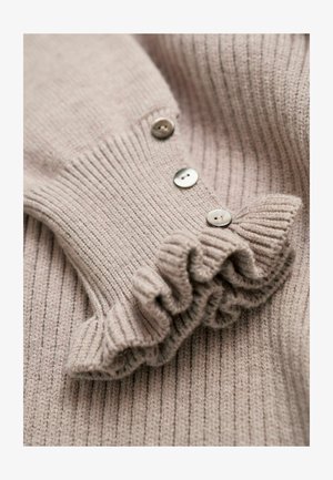 Helle rosa gerippte Pullovernähe mit einem Rüschensaum und drei runden Knöpfen mit einer glatten metallischen Oberfläche. Weicher, strukturierter Strickstoff.