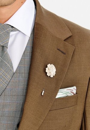 Brązowa, dopasowana marynarka garniturowa z przypinką w kształcie białego kwiatu na klapie, w połączeniu z wzorzystą szarą kamizelką i białą koszulą z poszetką.