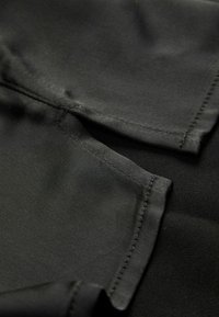 Tecido preto com uma textura suave e acabamento mate, exibindo costuras limpas e um design simples e discreto.