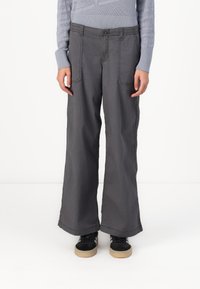 Gray wide-leg pants made of cotton with visible stitching, two front pockets, and a relaxed fit. Paired with black sneakers.