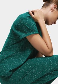 Zielone piżamy z krótkimi rękawami, wykonane z teksturowanej tkaniny i w rozproszony wzór w różowe i białe kropki. Krój jest luźny i wygodny.