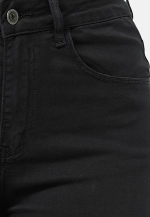 Jeans de mezclilla negra con una textura suave, diseño clásico de cinco bolsillos y cierre de botón de metal en la cintura.