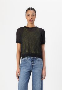 Black sheer short-sleeve top with a scoop neckline, layered over a green tank. Paired with light blue wide-leg jeans, featuring faded details.