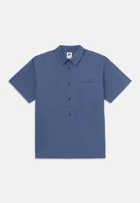 Modrá košeľa s krátkym rukávom vyrobená z bavlny, s gombíkovou prednou stranou, golierom a vreckom na ľavej strane; zobrazené logo Nike.