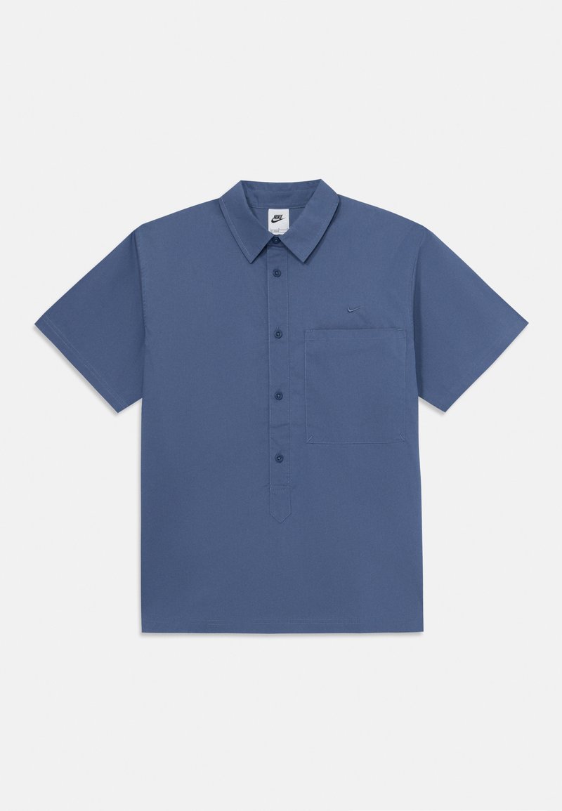 Srajca s kratkimi rokavi, modra, izdelana iz bombaža, z gumbi spredaj, ovratnikom in žepom na levi strani; prikazan logotip Nike.